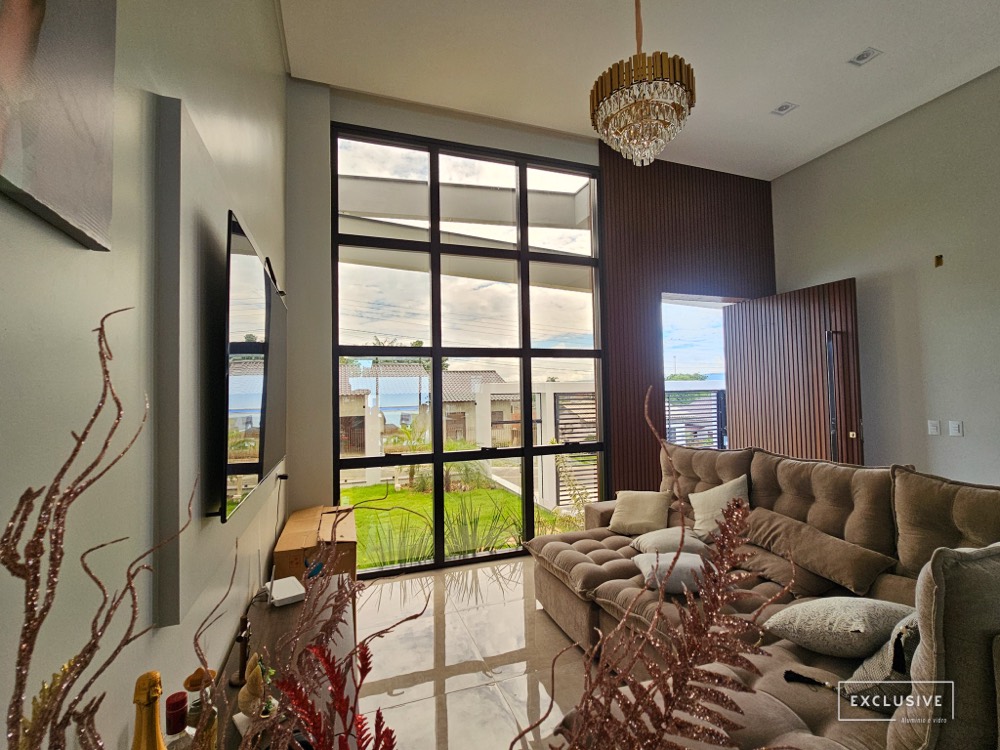 Sala com grande pano de vidro em perfis pretos de alumínio
