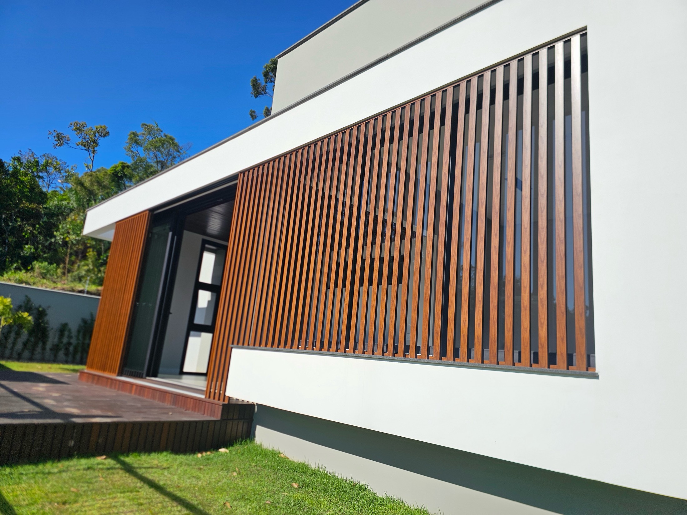 Casa moderna com brises verticais de alumínio em acabamento amadeirado